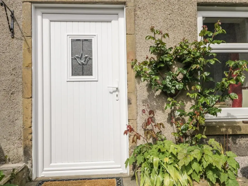a white door on a house with a plant at Fishermans Rest in Burghead