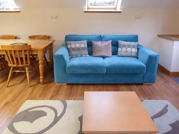 a living room with a blue couch and a table at Lakefield Apartment in Bearnock