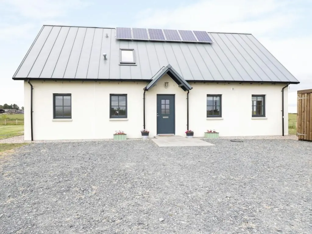 a white house with solar panels on the roof at Chance Inn Lodge in Balmedie