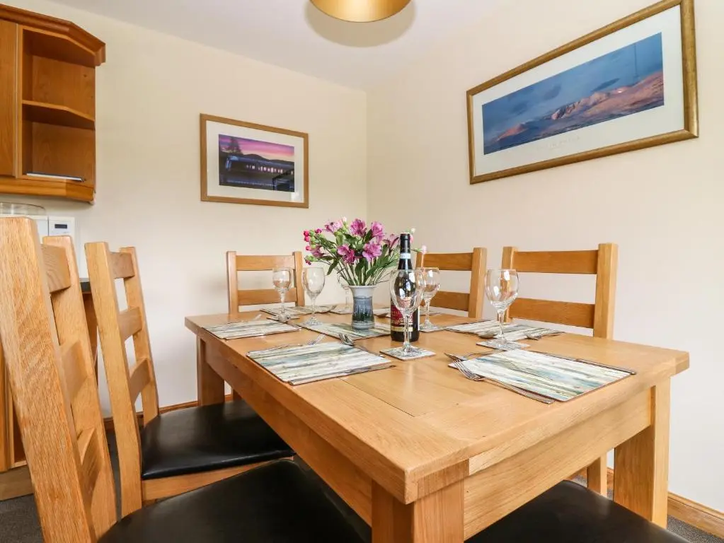 a wooden dining room table with chairs and flowers on it at Birchbank in Skye of Curr