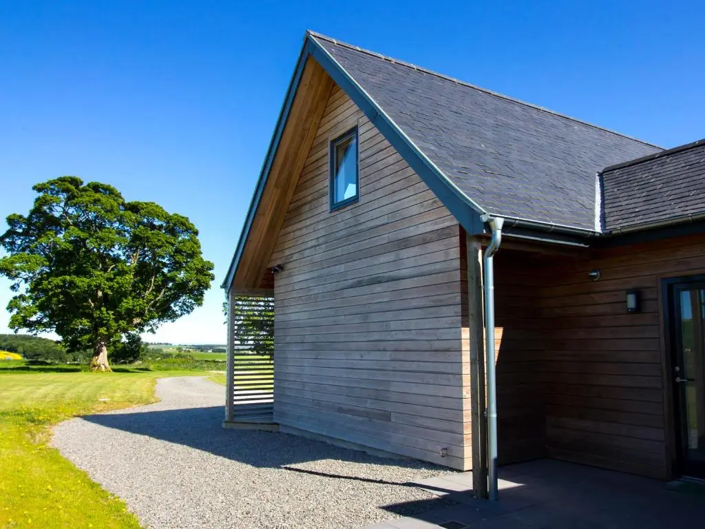 a wooden building with a tree in the background at Nef-Stedi in Kirktown of Bourtie