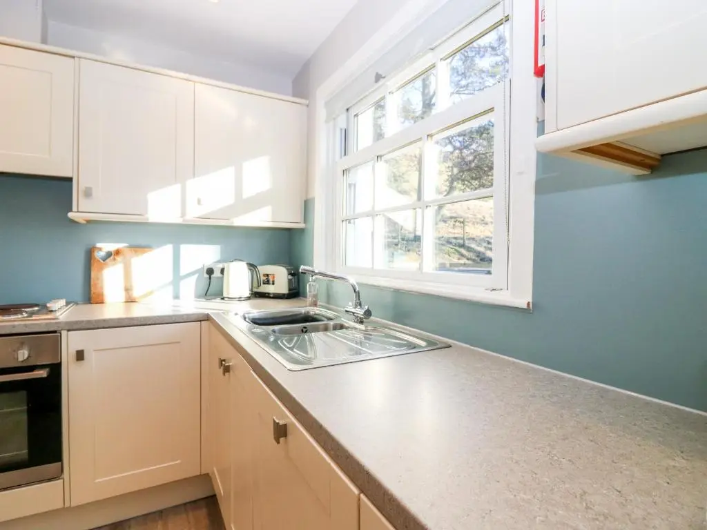 a kitchen with white cabinets and a sink and a window at White Hillocks Cottage in Inchmill