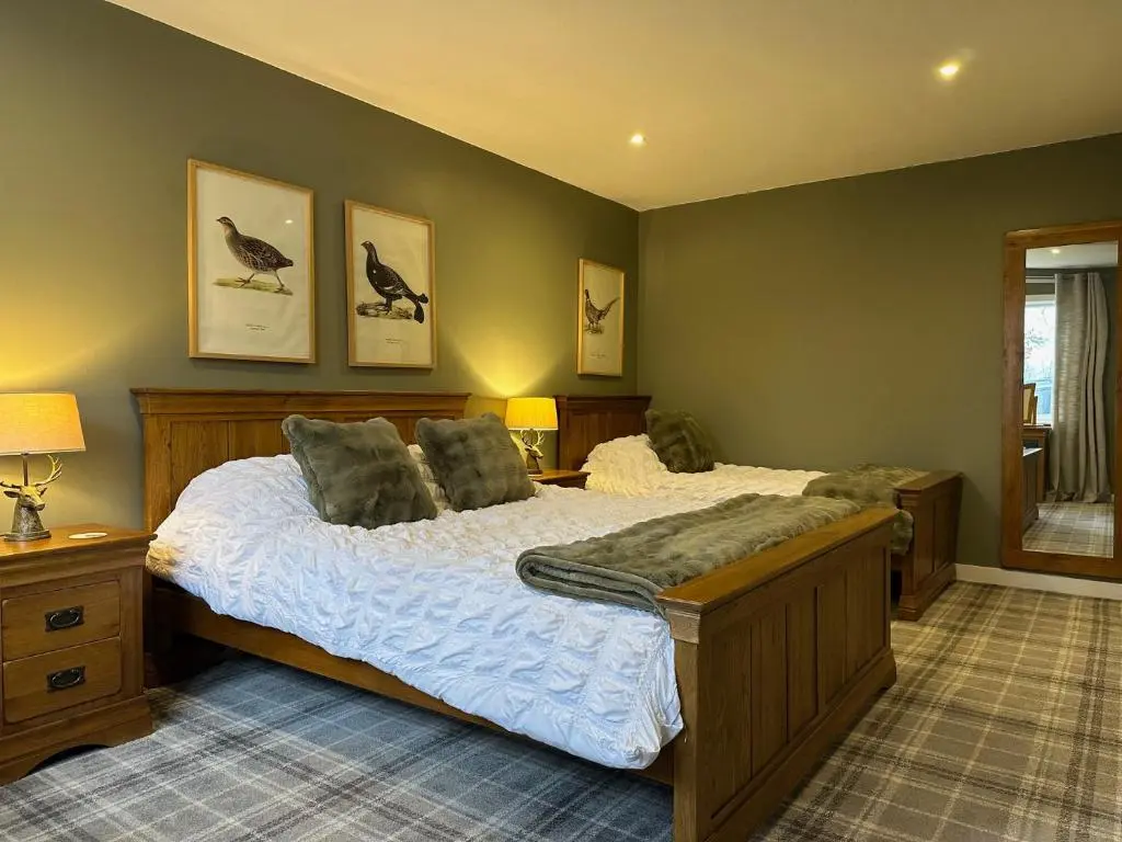 a bedroom with a large bed with birds on the wall at White Hillocks Cottage in Inchmill