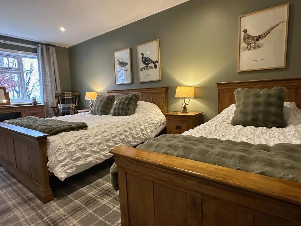 a bedroom with two beds and a window at White Hillocks Cottage in Inchmill