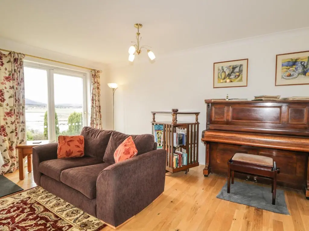 a living room with a couch and a piano at Glaven in Bonar Bridge
