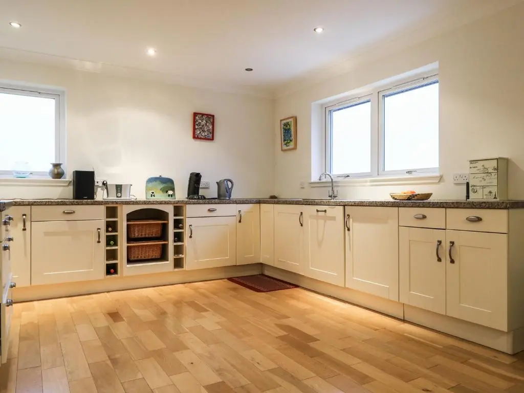 a kitchen with white cabinets and two windows at Glaven in Bonar Bridge