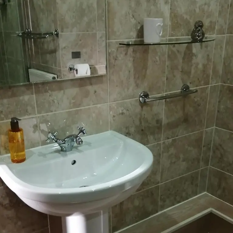 a bathroom with a white sink and a shower at Buttermere Cottage in Banff