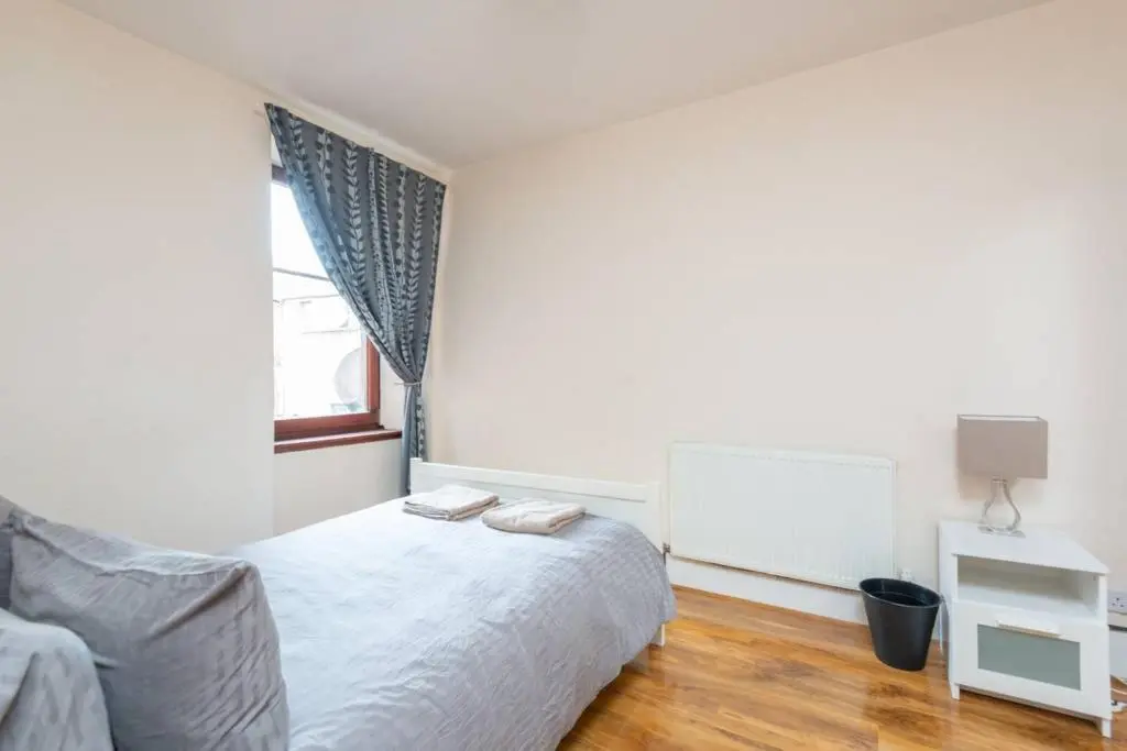 a white bedroom with a bed and a window at Ness Central Apartment - Greig Street in Inverness