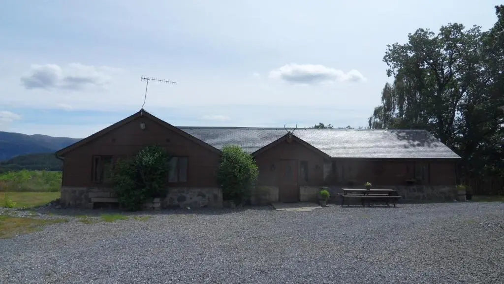 a barn with a picnic table in front of it at Meadowside Cottages in Balavil