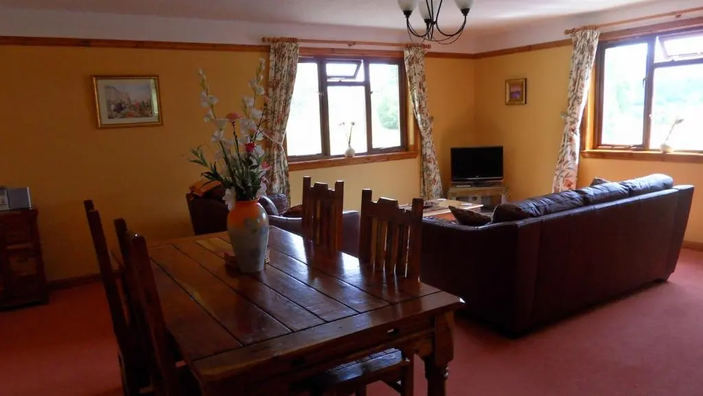 a living room with a wooden table and a couch at Meadowside Cottages in Balavil