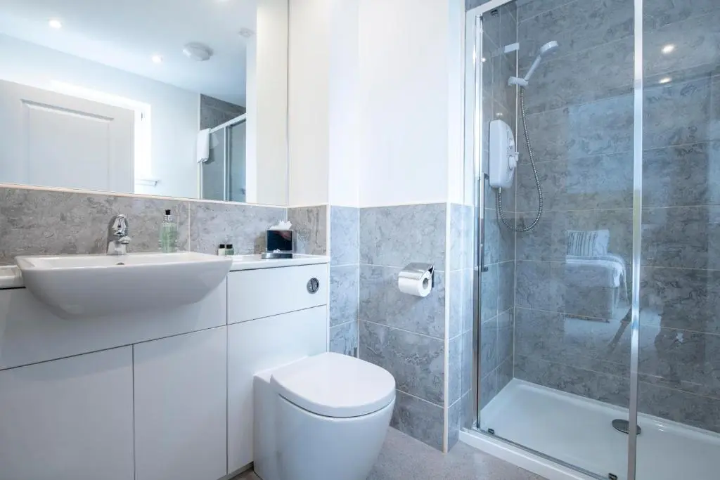 a bathroom with a toilet and a sink and a shower at Inverness City Suites in Inverness