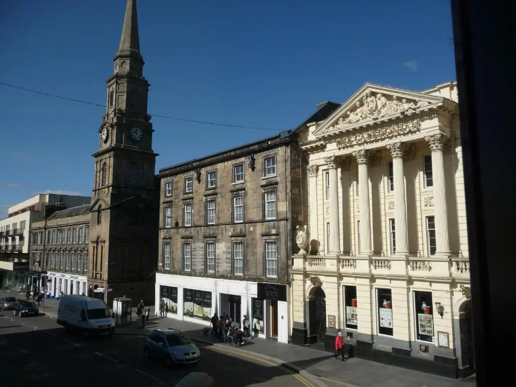 an old building with a clock tower on a street at Inverness City Suites in Inverness