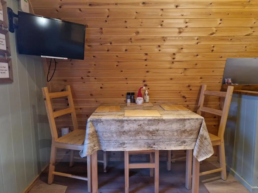 a dining room table with chairs and a flat screen tv at Hillside Havens in Dufftown