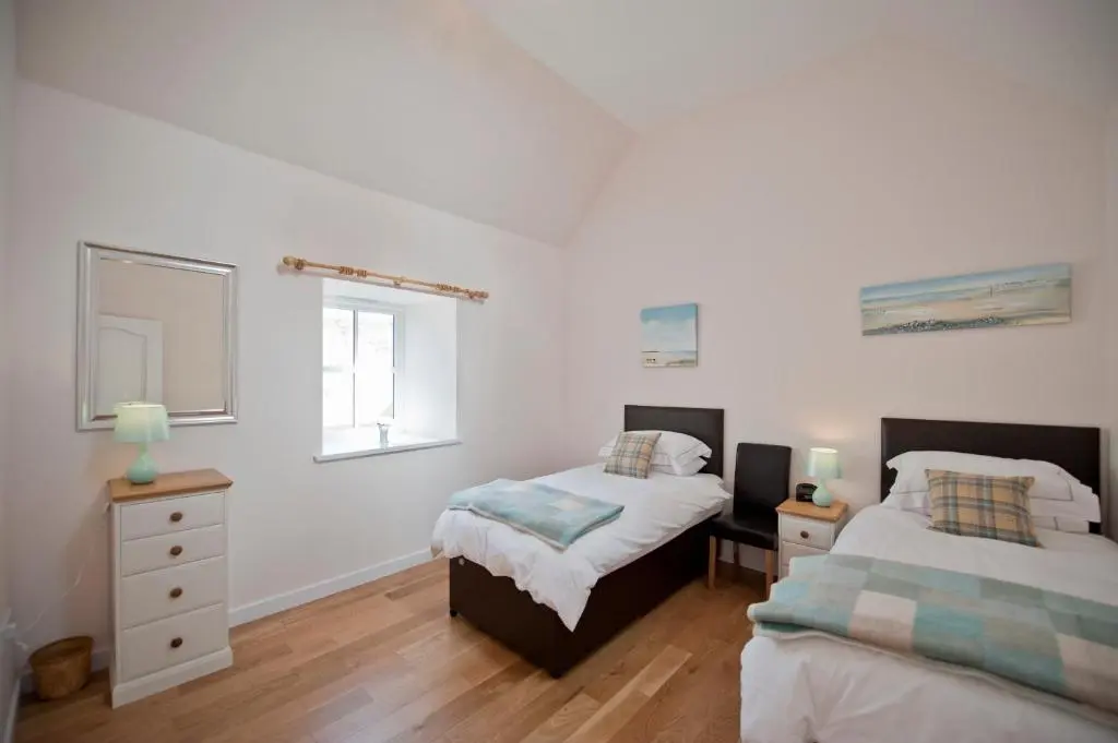 two beds in a bedroom with white walls and wooden floors at Lady Macbeths Rest in Banchory