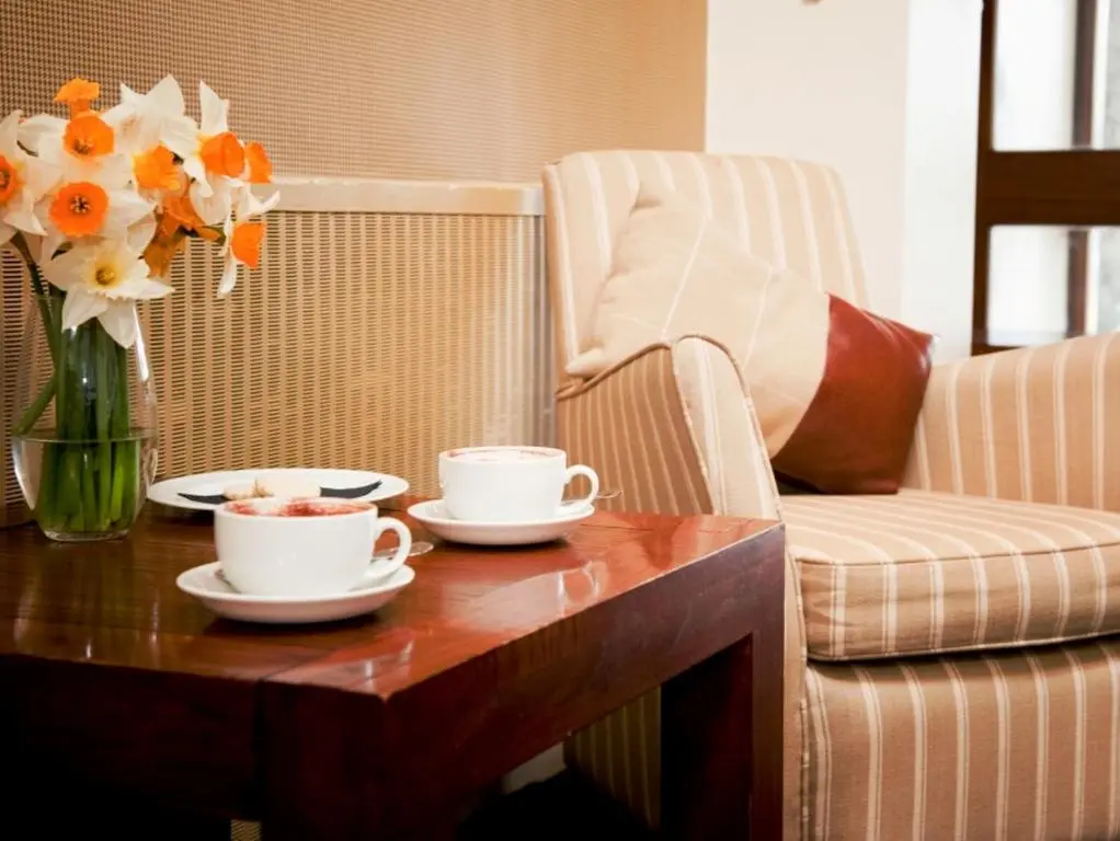 a coffee table with two cups and a vase of flowers at Norseman Hotel in Wick