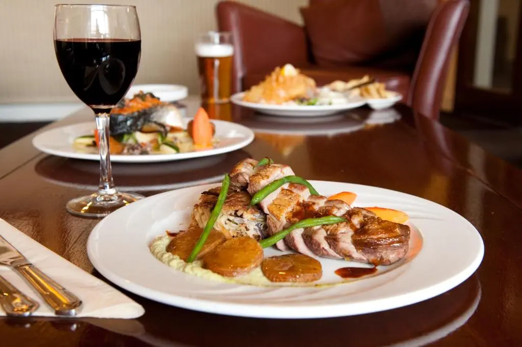 a table with plates of food and a glass of wine at Norseman Hotel in Wick