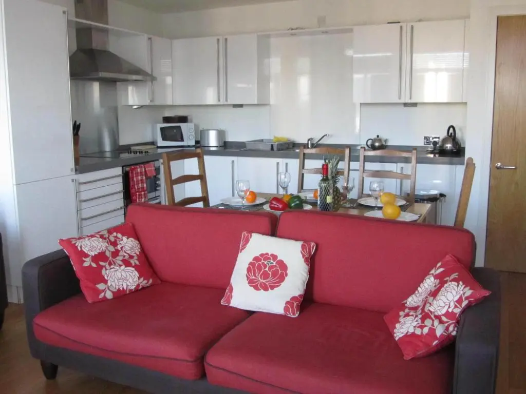a living room with a red couch and a kitchen at Bridge Street Apartments in Inverness