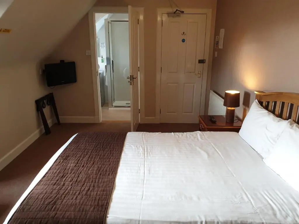 a bedroom with a large white bed and a television at Commercial Hotel in Alness