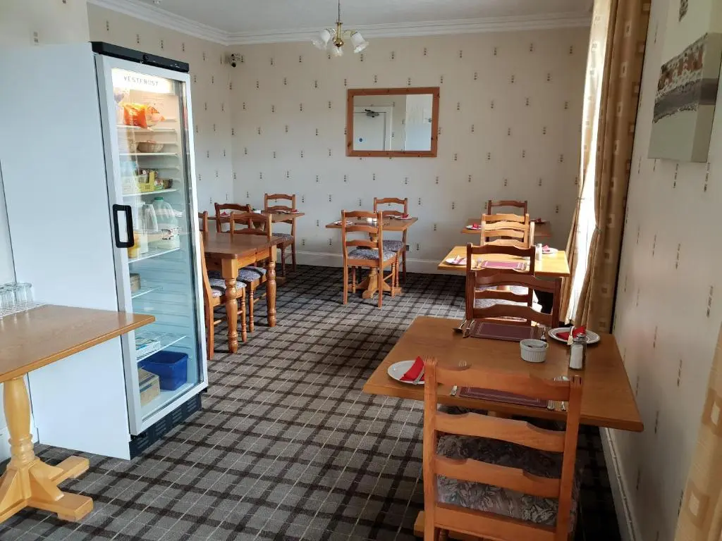 a dining room with tables and chairs and a refrigerator at Commercial Hotel in Alness