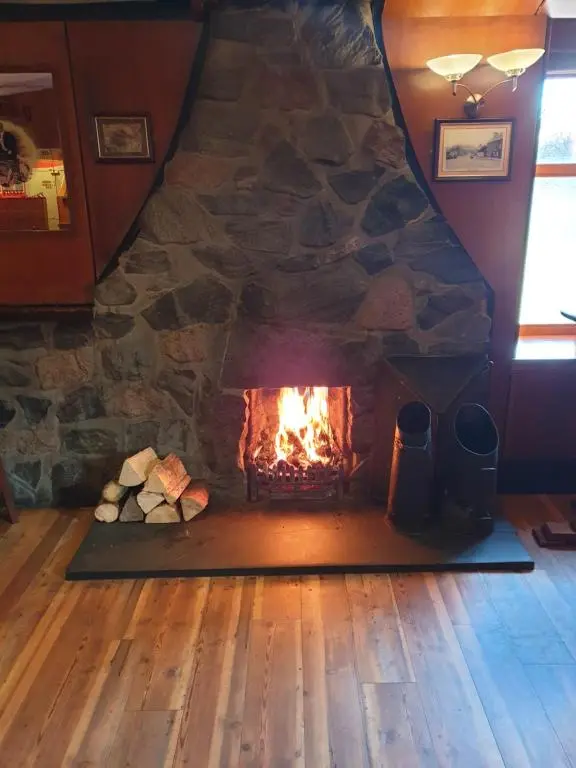 a fireplace in a room with a stone wall at Commercial Hotel in Alness