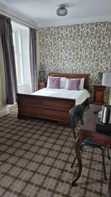 a bedroom with a large bed and a table at Commercial Hotel in Alness