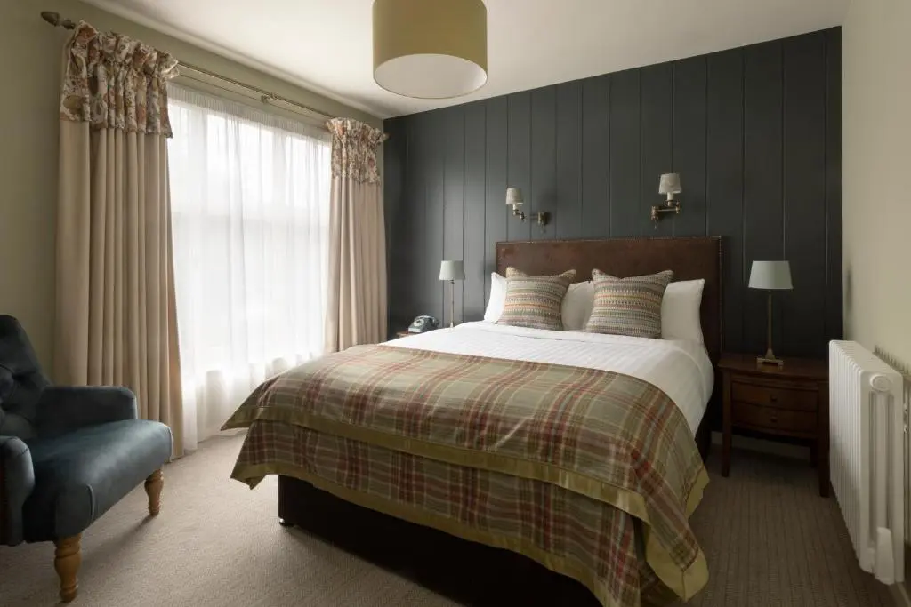 a bedroom with a bed and a chair and a window at Balmoral Arms in Ballater