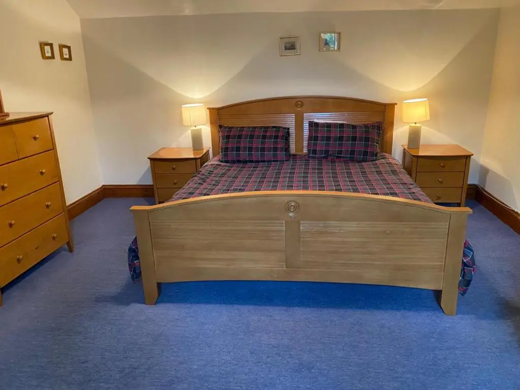 a bedroom with a wooden bed and two night stands at Parkmore Holiday Cottages in Dufftown