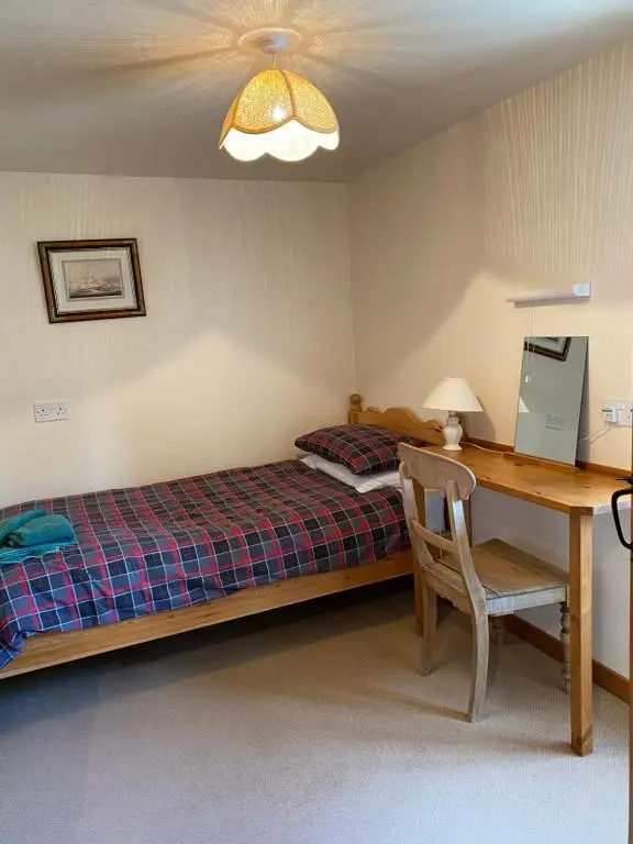 a bedroom with a bed and a desk and a table at Parkmore Holiday Cottages in Dufftown