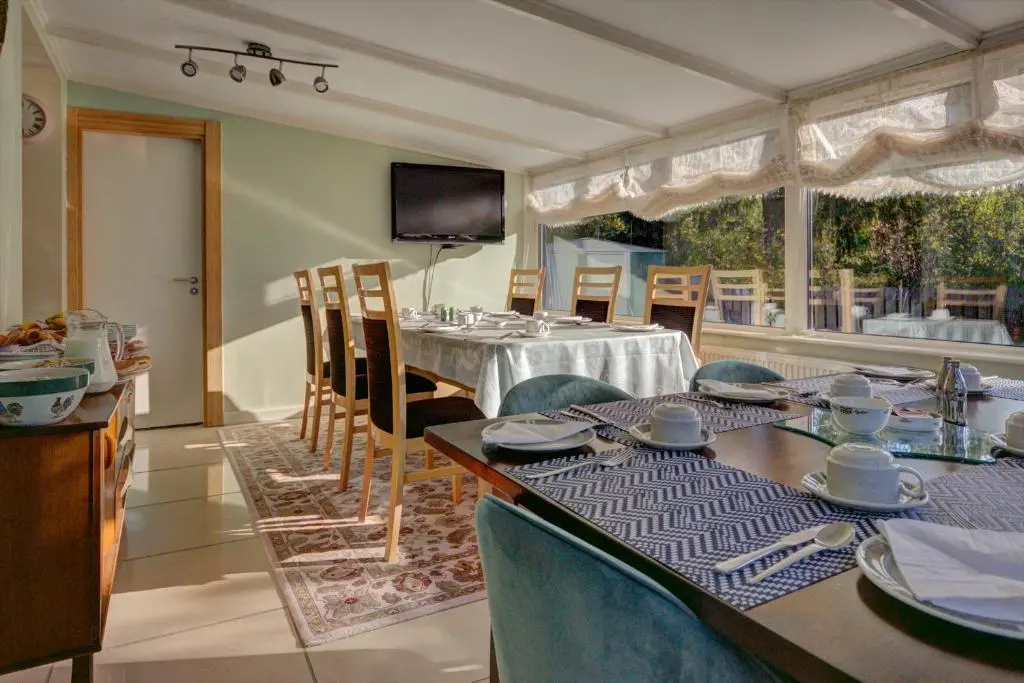a dining room with a table and chairs and a television at Loch Earn in Inverness