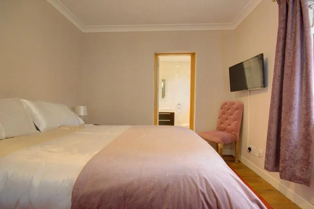 a bedroom with a bed and a chair and a television at Loch Earn in Inverness