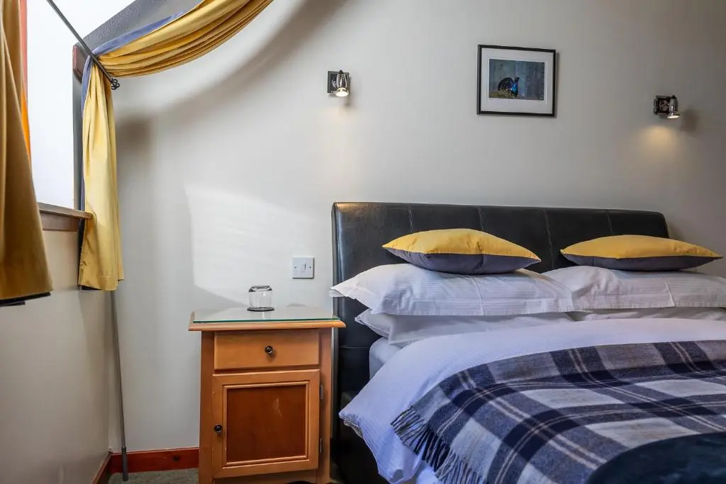 a bedroom with two beds and a nightstand with two pillows at Crubenbeg Country House in Newtonmore