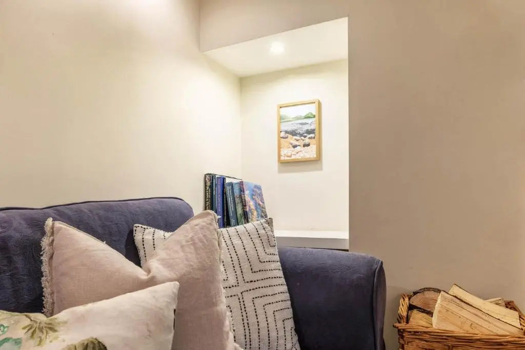 a living room with a blue couch with pillows at Riverside Cottage with wood fired hot tub in Cairngorms in Ballater