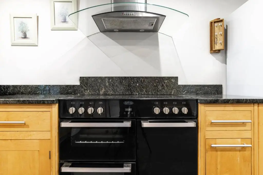 a black stove top oven in a kitchen at Riverside Cottage with wood fired hot tub in Cairngorms in Ballater