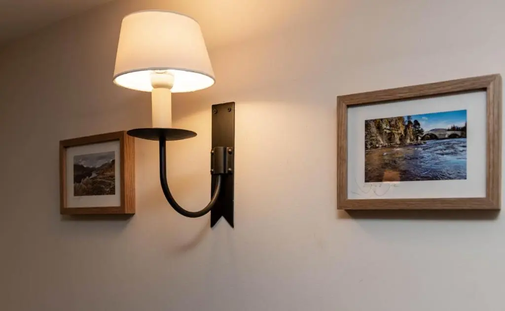 a light on a wall with two pictures at Riverside Cottage with wood fired hot tub in Cairngorms in Ballater
