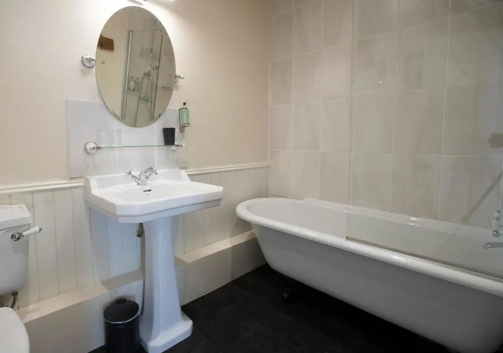a bathroom with a sink and a tub and a mirror at Cardhu Country House in Aberlour