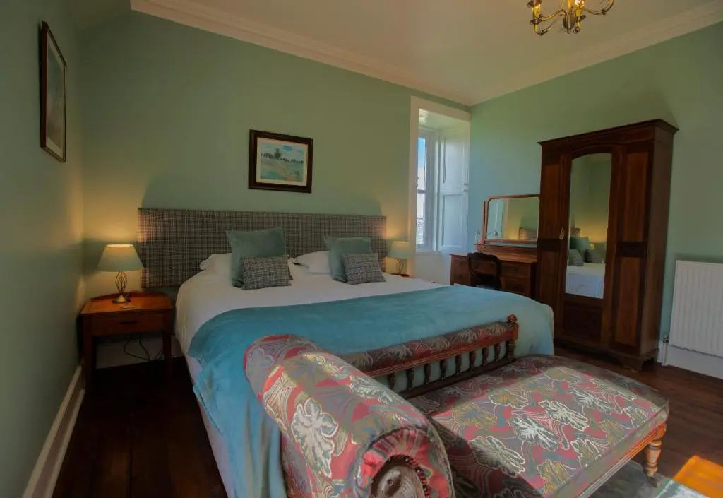 a bedroom with a large bed and a couch at Cardhu Country House in Aberlour