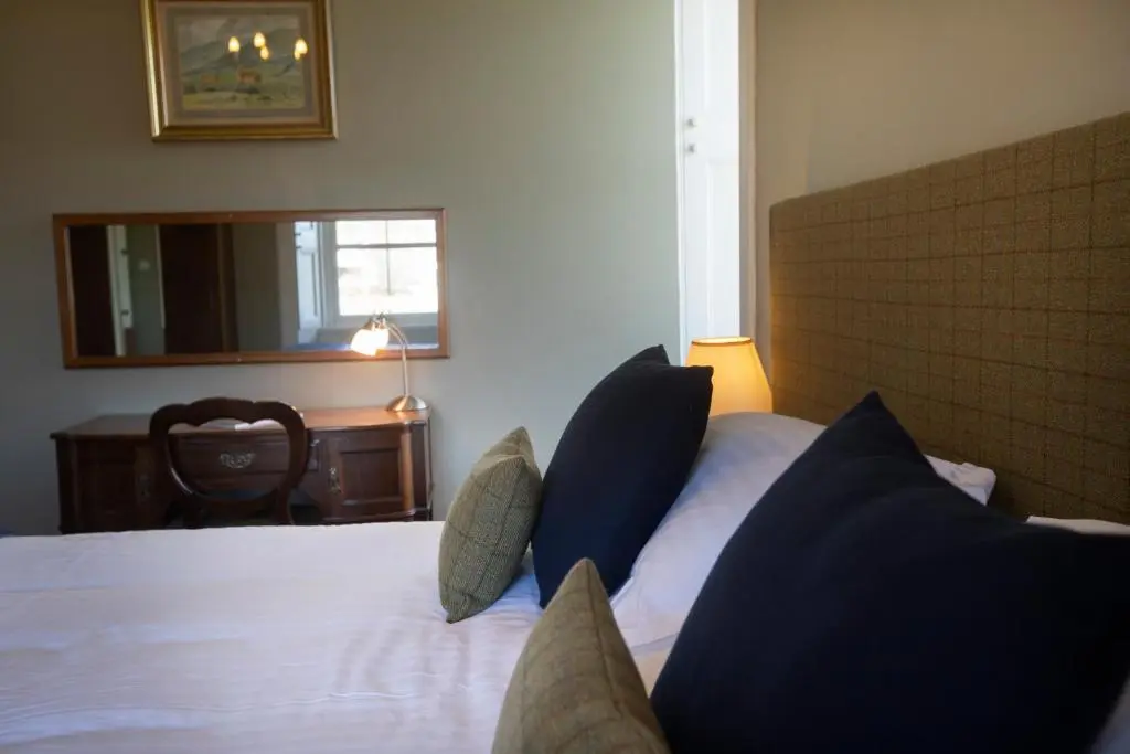 a bedroom with a bed with blue pillows and a mirror at Cardhu Country House in Aberlour