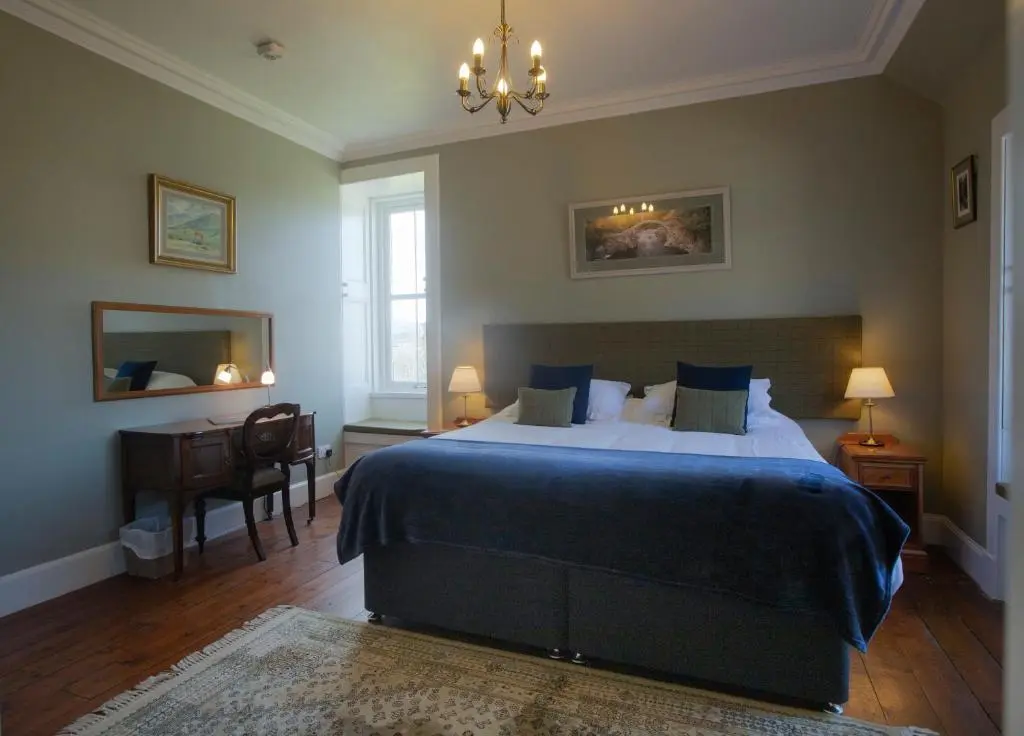 a bedroom with a bed and a desk and a chair at Cardhu Country House in Aberlour