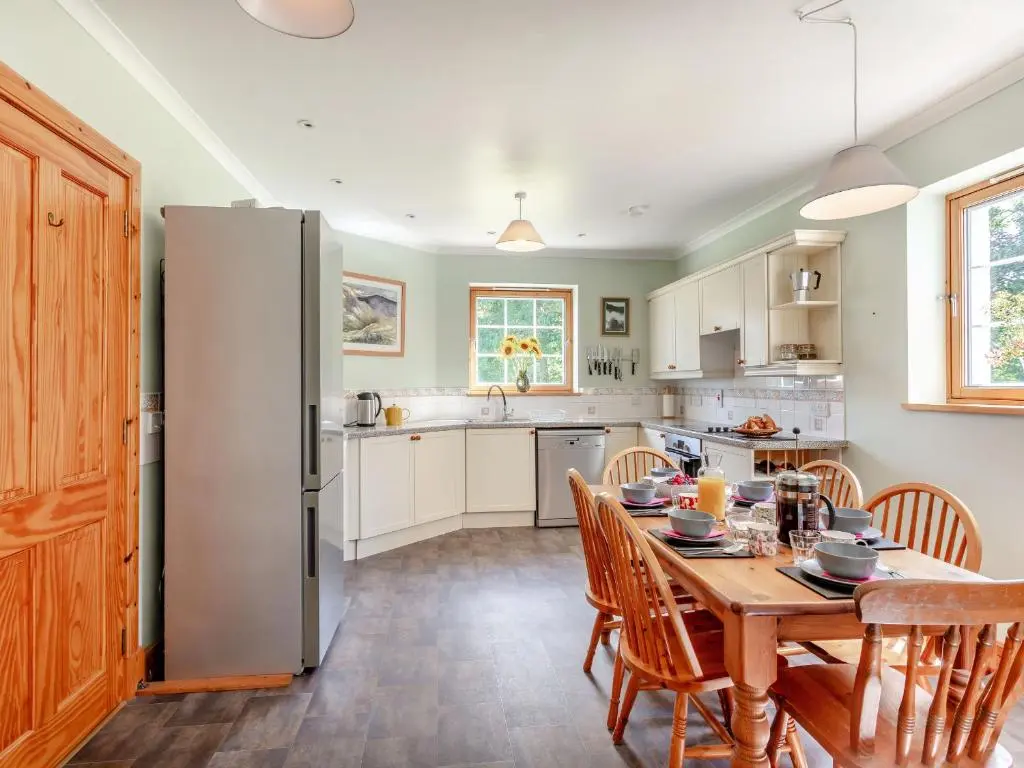a kitchen with a table and a refrigerator at The Old Laundry in Grantown on Spey