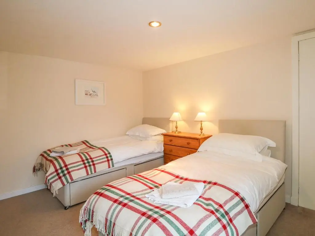 two beds in a small bedroom with two lamps onweredwered at Newlands in Archiestown