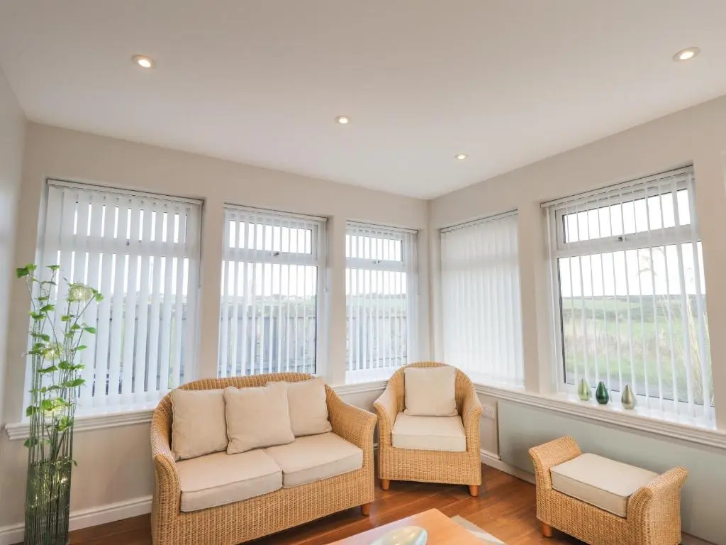 a living room with two chairs and windows at Rose Cottage in Lybster