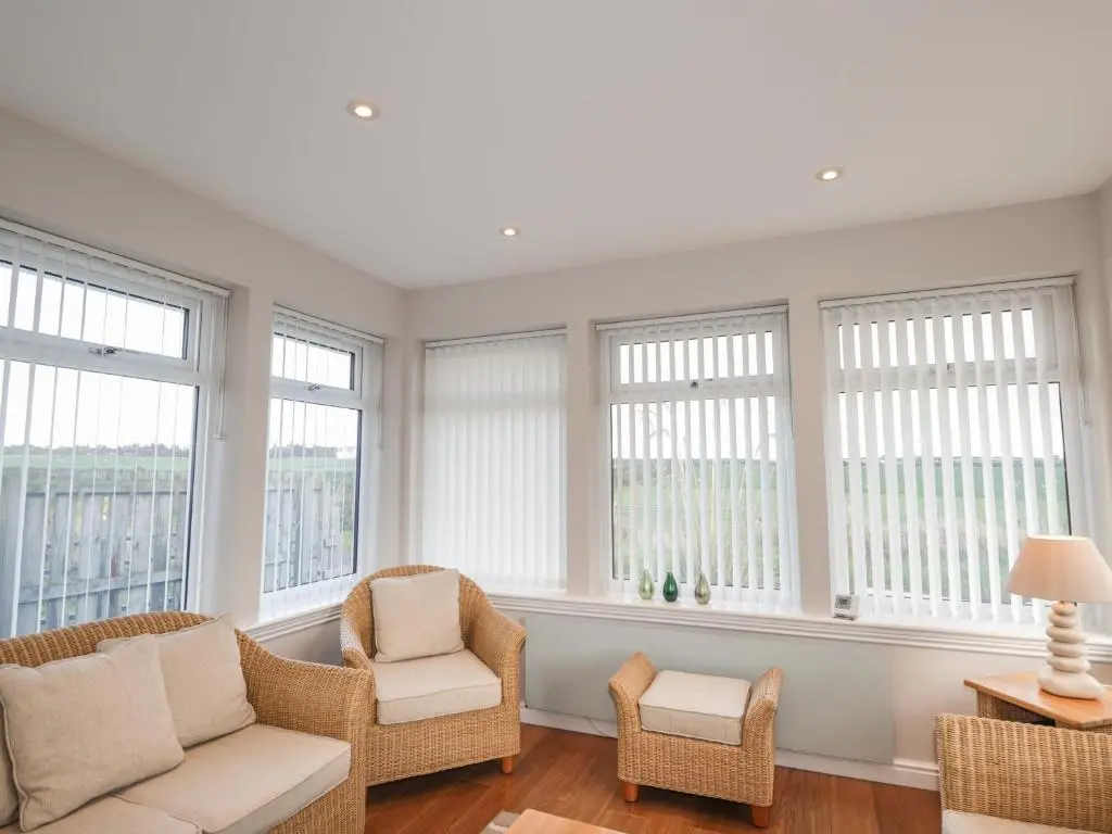 a living room with a couch and chairs and windows at Rose Cottage in Lybster