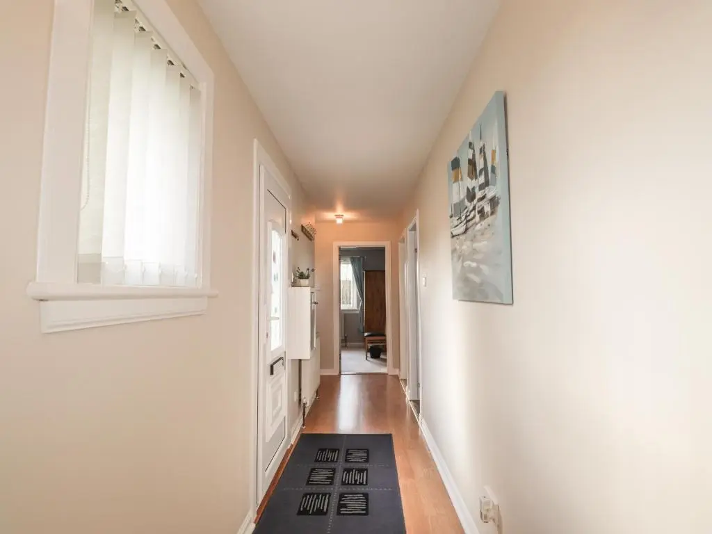a hallway with white walls and a rug on the floor at Rose Cottage in Lybster