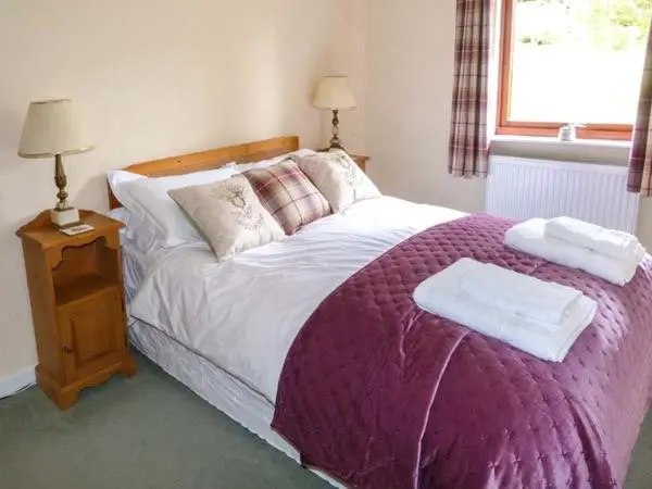 a bedroom with a bed with two towels on it at Pine Lodge in Resolis