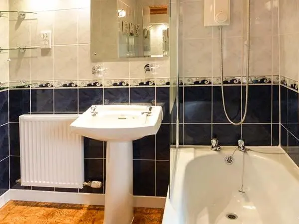 a bathroom with a sink and a bath tub next to a sink at Pine Lodge in Resolis