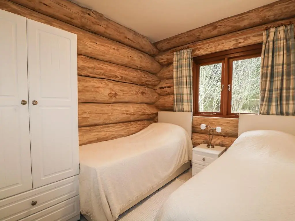 a bedroom with two beds in a log cabin at Heron Lodge in Inverness