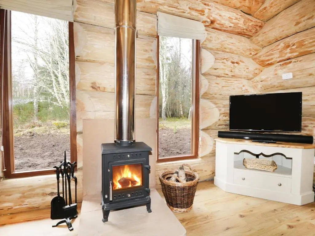 a log cabin living room with a wood stove at Heron Lodge in Inverness