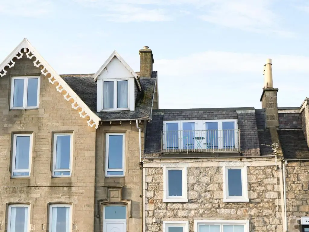 an old brick building with a balcony on top of it at Seascape in Lossiemouth
