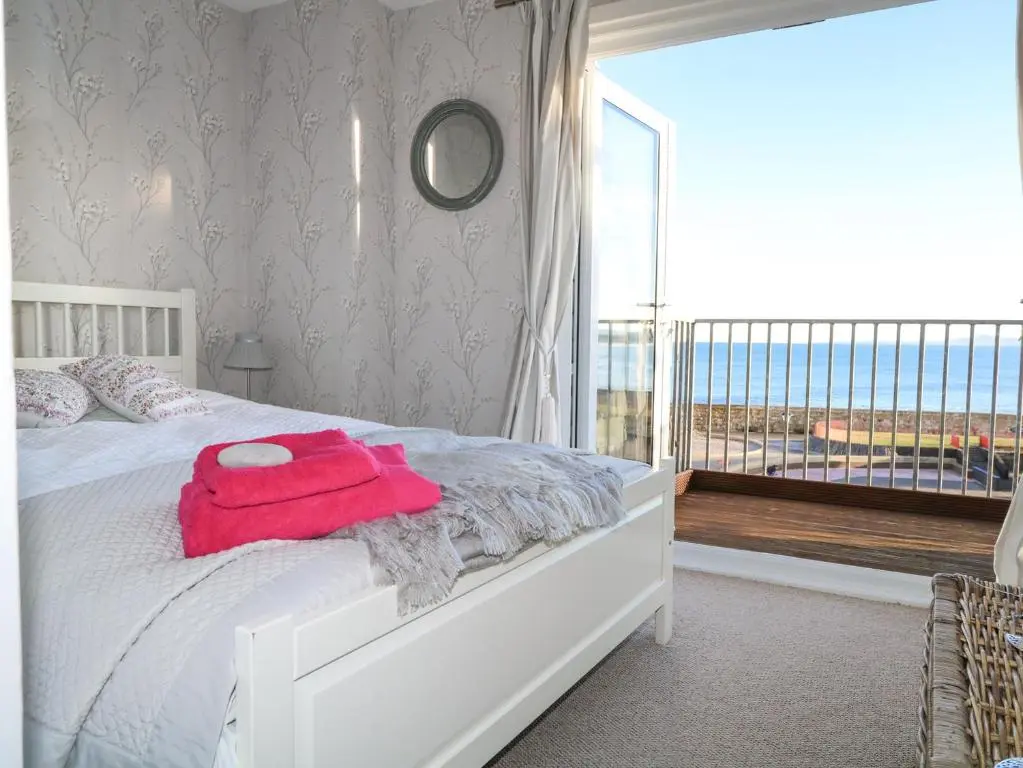 a bedroom with a white bed and a large window at Seascape in Lossiemouth