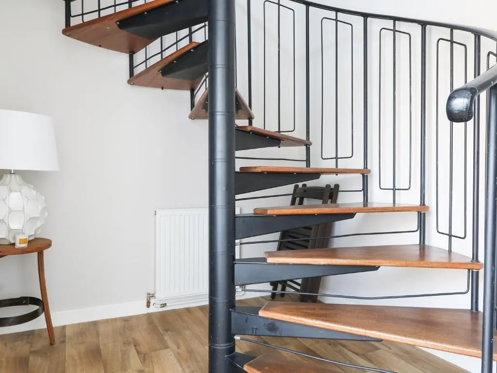 a metal spiral staircase with wooden steps in a living room at Seascape in Lossiemouth